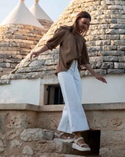 Nomad Cropped Sailor Jean 21 Nomad Cropped Sailor Jean -Mersea womens patch pocket stretchy cropped wide leg white jeans side view travel destination look walking stairs