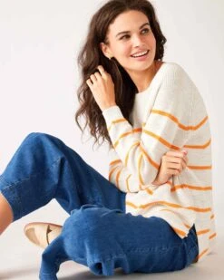 Camden Boatneck Sweater -Mersea womens white orange stripes midweight sweater sitting side view arms crossed